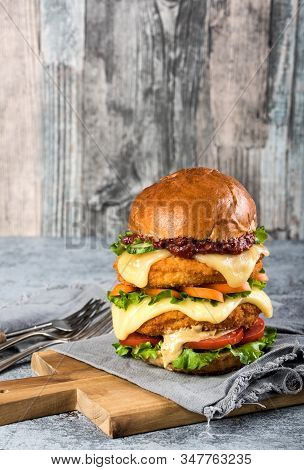 Homemade Chicken Burger With Fried Egg Tomato Lettuce Cucumber Dripping Mozzarella On Cutting Board 