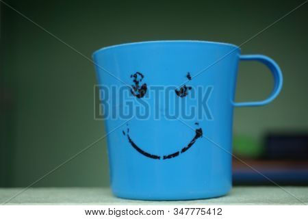 Close Up The Smile On The Plastic Water Mug Blue Color.