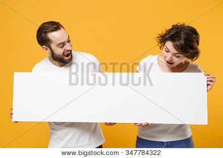 Curious Young Couple Friends Bearded Guy Girl In White T-shirts Isolated On Yellow Orange Background