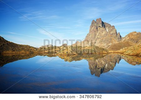 Midi Dossau Peak reflected in a lake. Ossau Valley, Pyrenees National Park, Pyrenees, France.