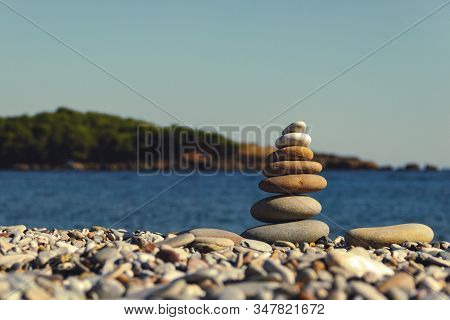 Pyramid Of Stones On The Beach. Stack Of Stones Against Blurred Seascape, Space For Text. Zen Concep