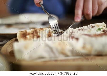 Person Cutting Kebab Wrapped In Pita