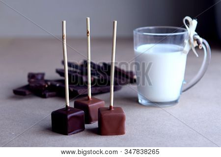 Chocolate Cubes On A Stick With Milk Cup And Aromatic Cocoa And Chocolate On Brown Background. Hot C