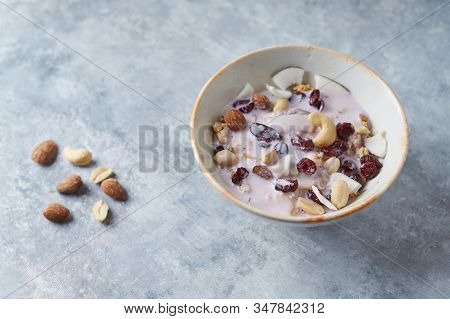 Bowl Of Granola With Yogurt, Nuts, Cranberry And Cocoanut On Bright Stone  Background.