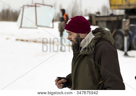 An Installer In Green Winter Workwear Walks Along An Assembly Site Against A Background