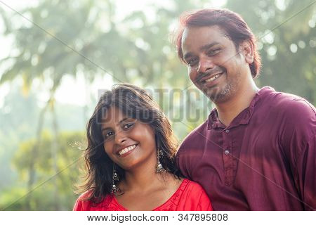 Young Attractive Indian Couple Feeling Tenderness And Hugging Each Other At Sunset Light , Palms Tre