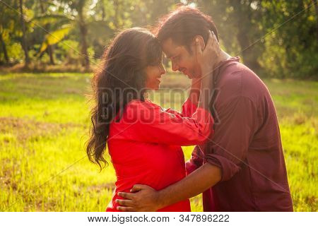 Young Attractive Indian Couple Feeling Tenderness And Hugging Each Other At Sunset Light , Palms Tre