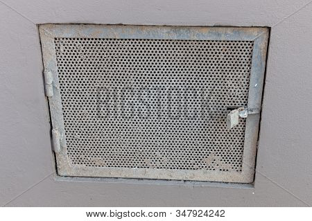 A Close Up View Of A Locked Metal Meshed Door Leading To A Passway Under A Building. Covered In Conc