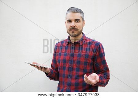 Annoyed Young Man Holding Smartphone And Looking At Camera. Stylish Guy Having Confused Look Facing 