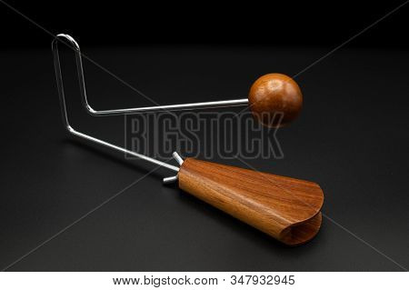 Closeup Of A Vibraslap Silver, Brown Wood On Black Underground
