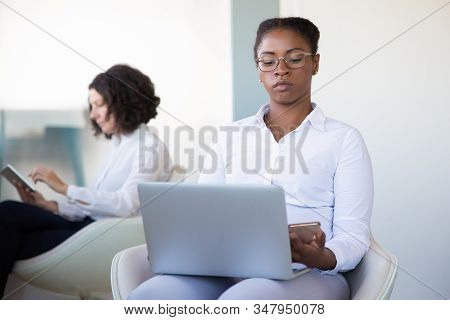 Businesswoman Using Laptop And Smartphone. Serious Young Businesswoman Wotking With Lapop Computer A