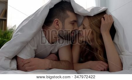 Tender Young Man And Woman Nuzzling Under Blanket, Lovers Enjoying Togetherness