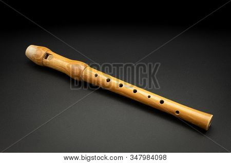 Closeup Of A Wooden Soprano Recorder Lying On Black Background