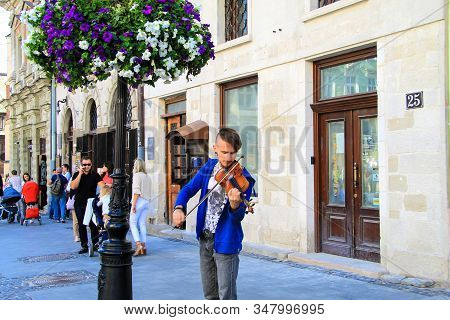 Lviv, Ukraine, 04 07 2019 A Young Man Plays The Violin On A Historic Street In Lvov. The Musician Vi