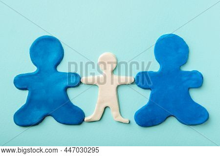 Two Blue Plasticine Identical Men As Same Parents Holding The Hand Of A White Plasticine Child On A 
