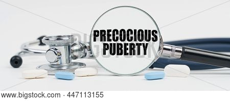 Medicine And Health Concept. On A White Surface Are Pills, A Stethoscope And A Magnifying Glass Insi