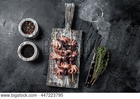 Skewers With Grilled Baby Mini Octopuses. Black Background. Top View
