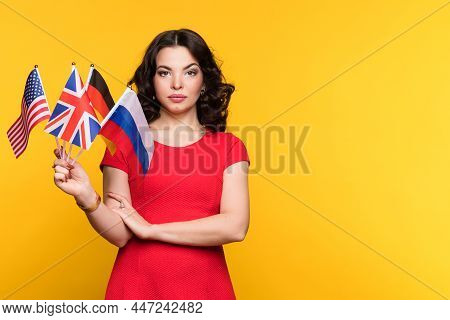 Female With Set Of Flags Of Different Countries Of The World Looking At Camera. Serious And Confiden