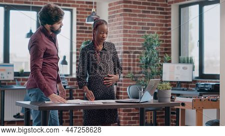 Business Man Helping Pregnant Woman With Project Planning At Workplace. Employee Expecting Child And