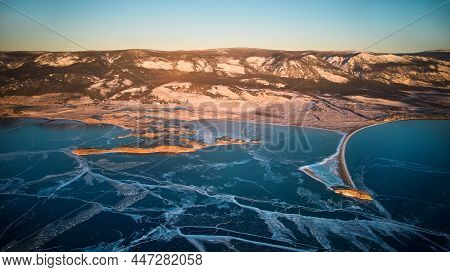 View Of The Frozen Lake Baikal In January. Transparent Ice With Cracks. Kurma Bay, Cape Uyuga From T