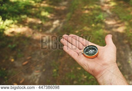 Compass In Hand At Forest. Tourist Compass For Orientation On The Terrain. Magnetic Declination Alcu