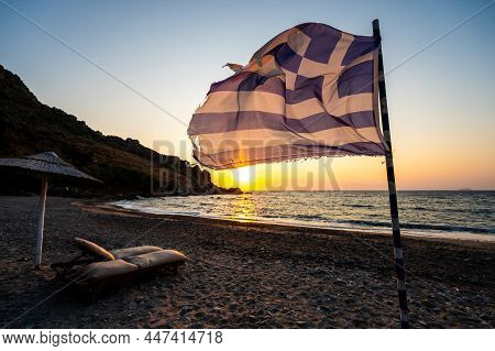 Greek Flag Waving At Sunset On A Sandy Beach In Crete, Greece.