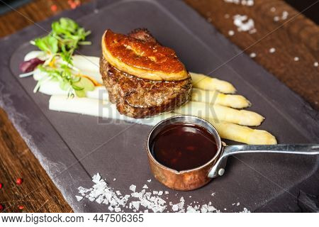 Tournedos Rossini. Foie gras, Black Angus beef tenderloin, white asparagus, red wine sauce. Delicious healthy traditional food closeup served for lunch in modern gourmet cuisine restaurant