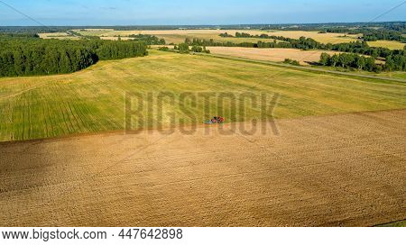 Scenic View Of Working Tractor In The Field Agricultural Field On A Summer Farm In The Evening. Aeri