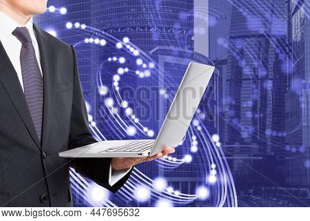 Attractive Young European Businessman Using Laptop With Creative Circular Light On Blurry City Backg