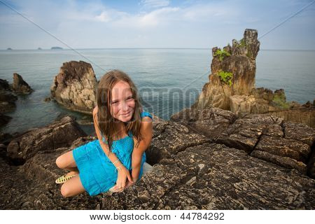 Teengirl in un abito blu nelle rocce della costa in Thailandia.