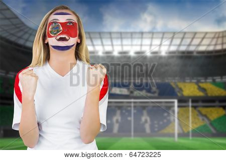 Excited costa rica fan in face paint cheering against football pitch in large stadium