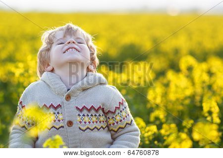 Happy Little Blond Toddler Boy Lauging In Yellow Rape Field On A Spring Day