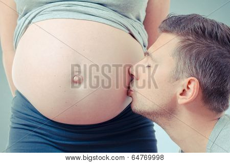 dad is kissing his pregnant wife