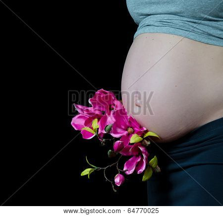 pregnant woman on black background with hands on her belly