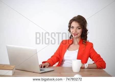 Attractive woman sitting at desk in office, working with laptop