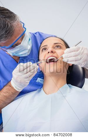 Dentist examining a patient with angle mirror and sickle probe in dental clinic