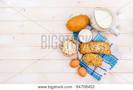 Breakfast of cheese, milk, bread and eggs on a light wooden background