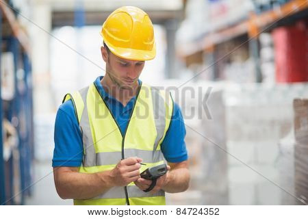 Worker using hand held computer in warehouse
