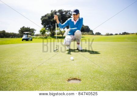 Female golfer putting her ball on a sunny day at the golf course