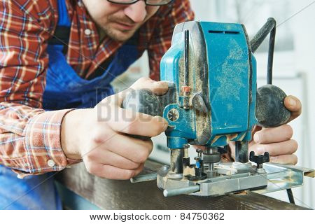 door installer working with milling cutter at preparing hole for hinge