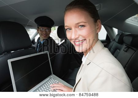 Businesswoman being chauffeured while working in the car