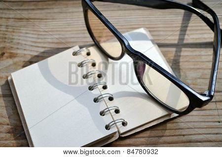 An empty retro spiral notebook with old paper and reading glasses