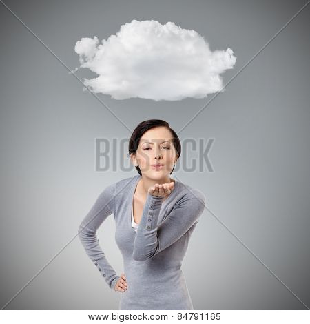 Beautiful girl blows a kiss, isolated on grey background with cloud