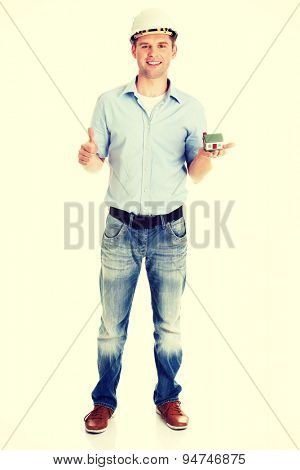 A forewoman holding a model house in hand and gesturing OK