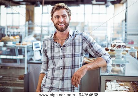 Selfassured waiter smiling in front of his bakery