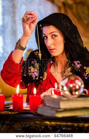 Fortuneteller radiesthesist in Seance dowsing with pendulum telling the future
