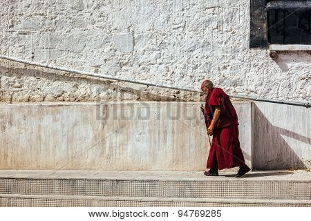 SPITUK, INDIA - SEPTEMBER 15, 2012: Old buddhist monk walking along the wall of Spituk gompa, Ladakh, India