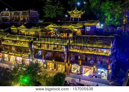 FENGHUANG CHINA - JUNE 14: Illuminated traditional Chinese architecture buildings in city's downtown by the river bank at night. June 2016