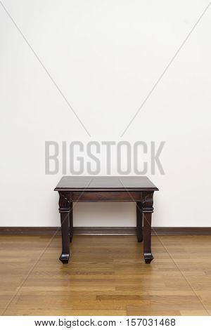 Hand made wooden side table against wall with copyspace