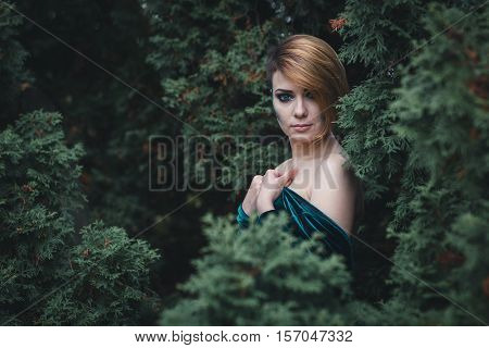 Portrait of a beautiful girl with bright make-up in the forest
